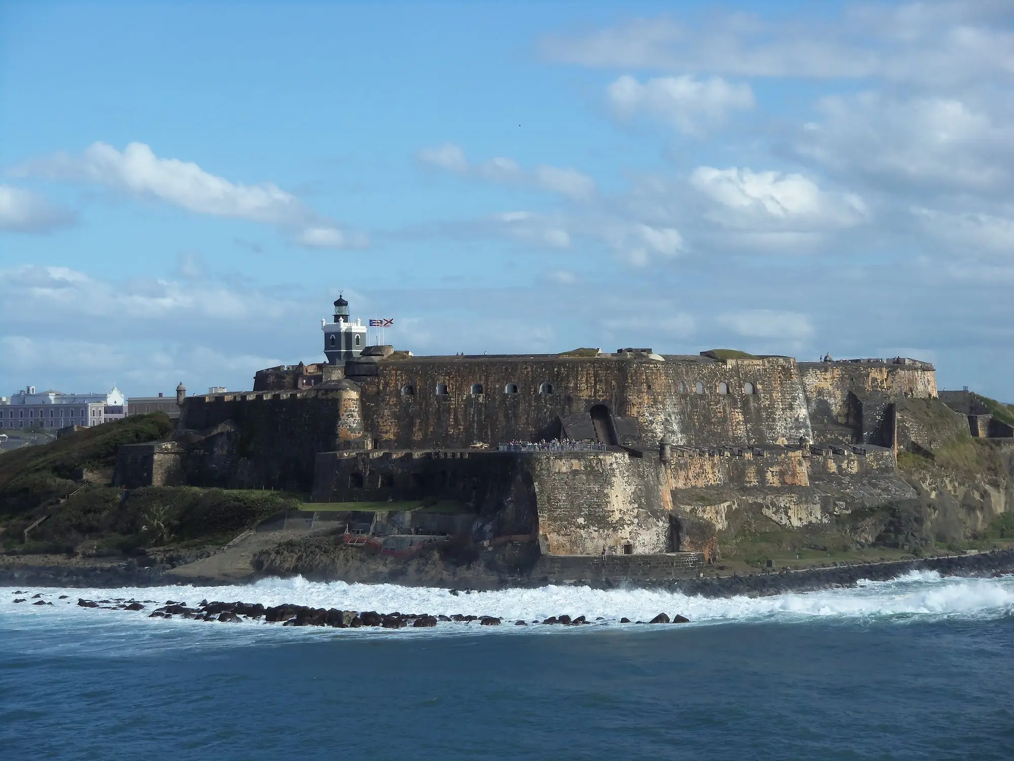 Castillo San Felipe del Morro seen from the sea, its stone walls and lighthouse on the headland at the entrance to San Juan Bay