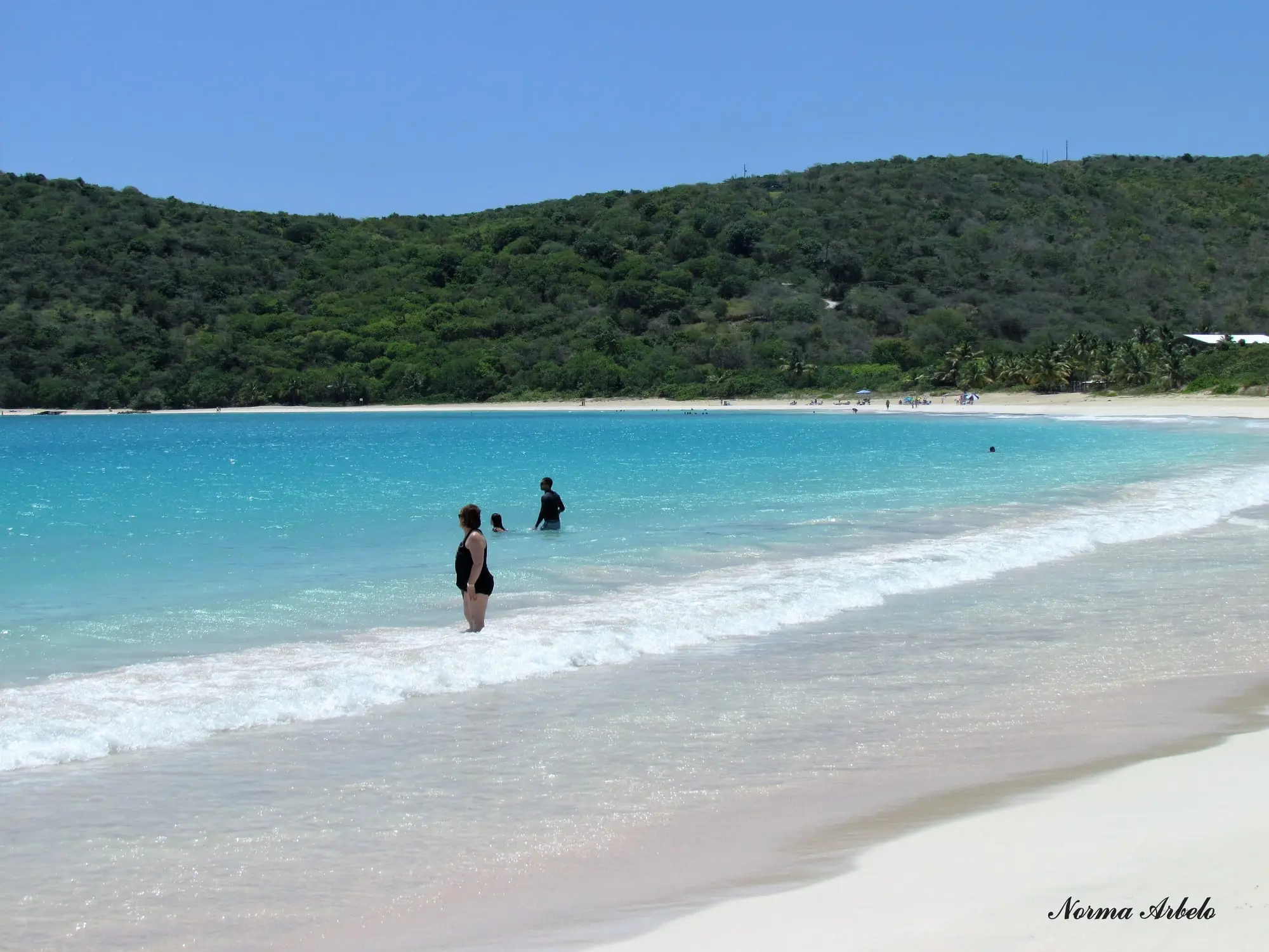 Turquoise water and white sand at Playa Flamenco, in its bay ringed by green hills