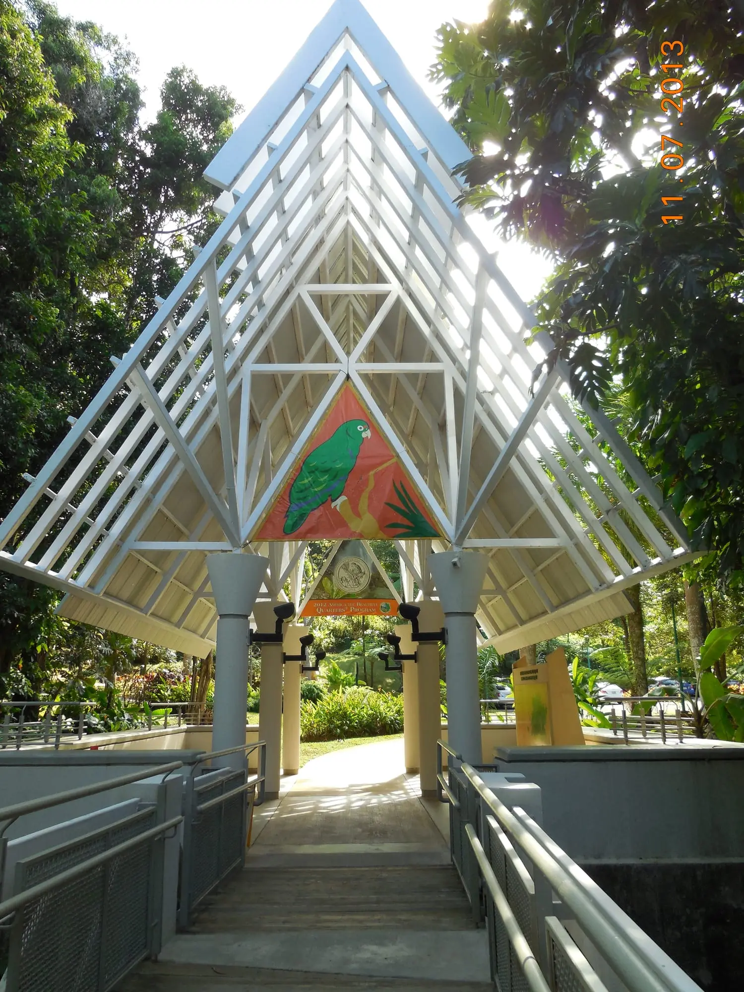 El pabellón de entrada, abierto y con techo en punta, del centro de visitantes El Portal de El Yunque, con un mural de una cotorra puertorriqueña