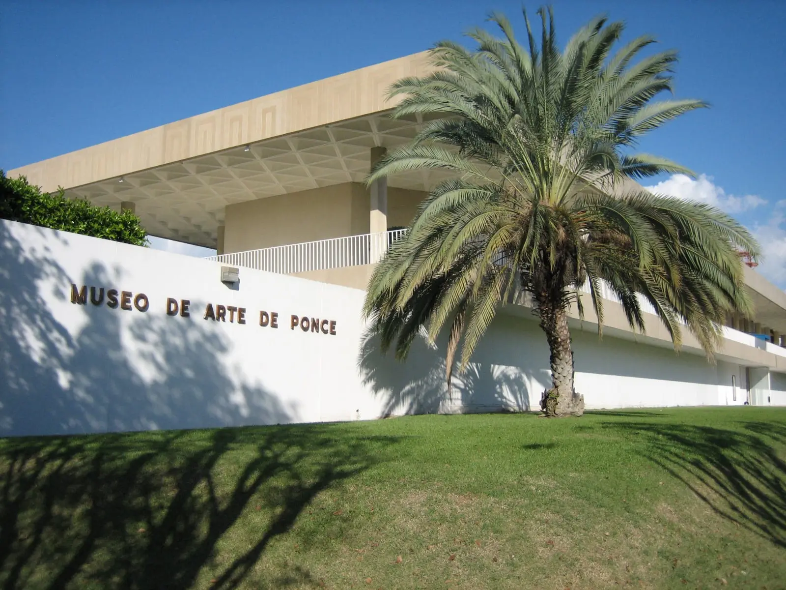The white modernist facade of the Museo de Arte de Ponce, with its name on the wall and a palm tree