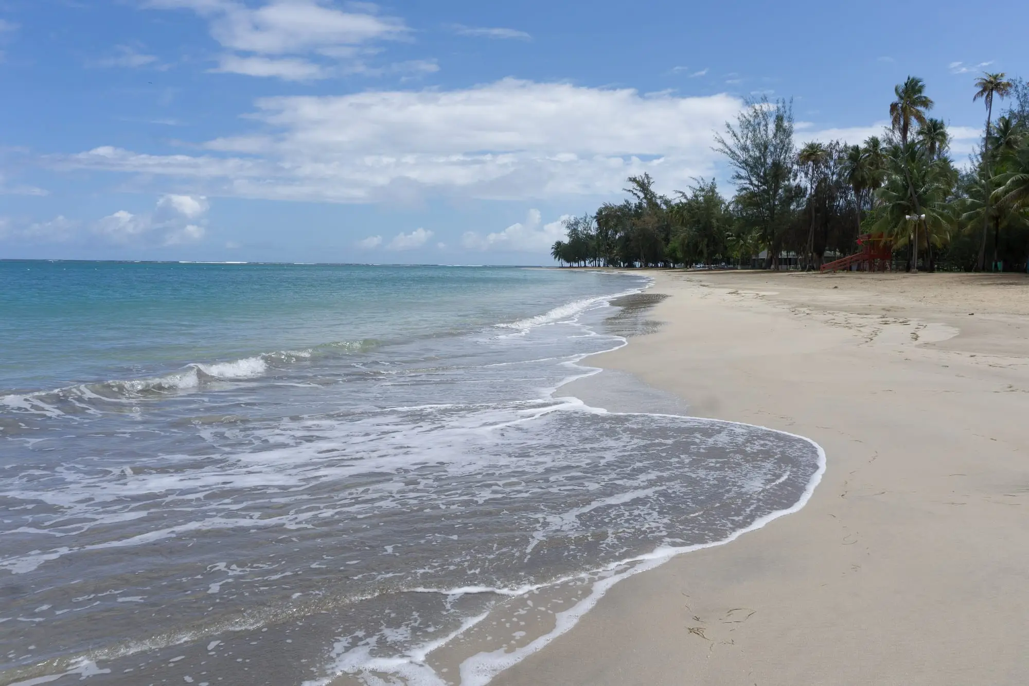 Luquillo beach (Balneario La Monserrate), a wide stretch of pale sand with gentle waves and a line of palm trees